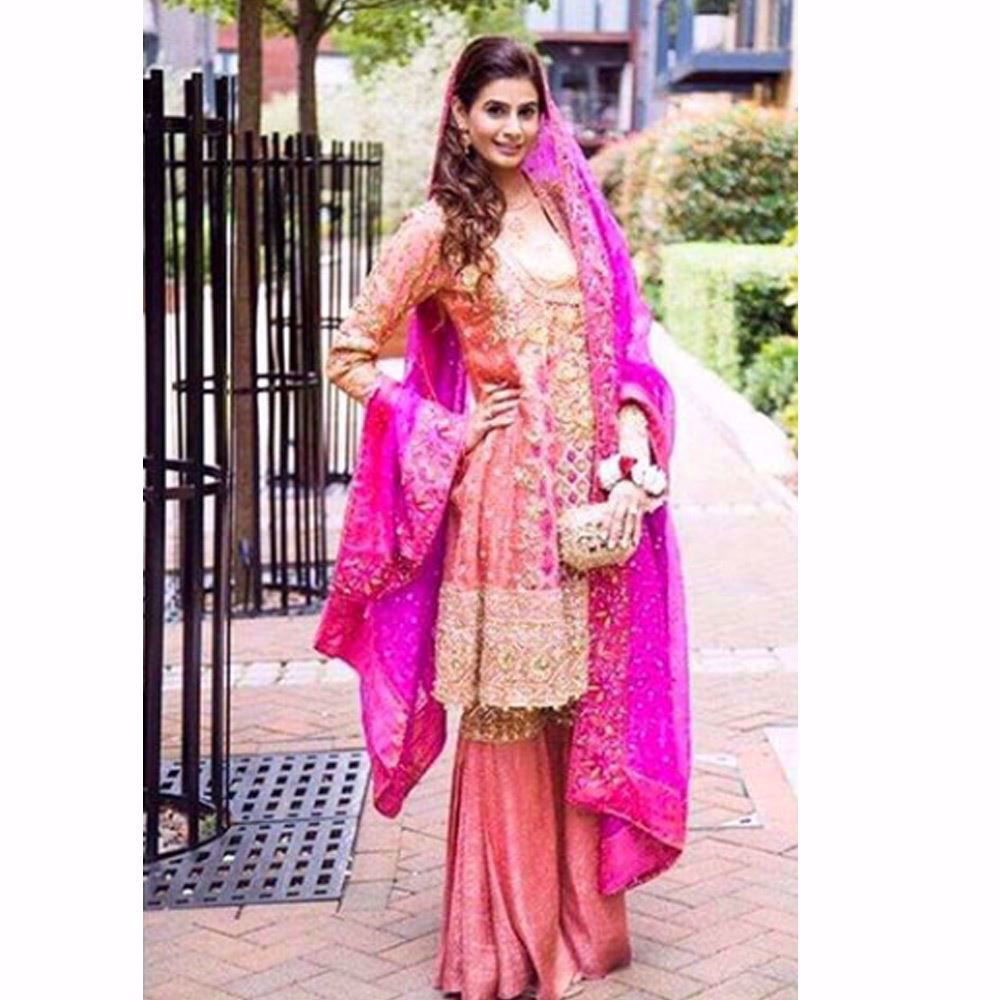 Picture of An absolute beauty on her Mehndi in a burnt orange Farah Talib Aziz kalidaar angarkha with festive bursts of pinks and greens