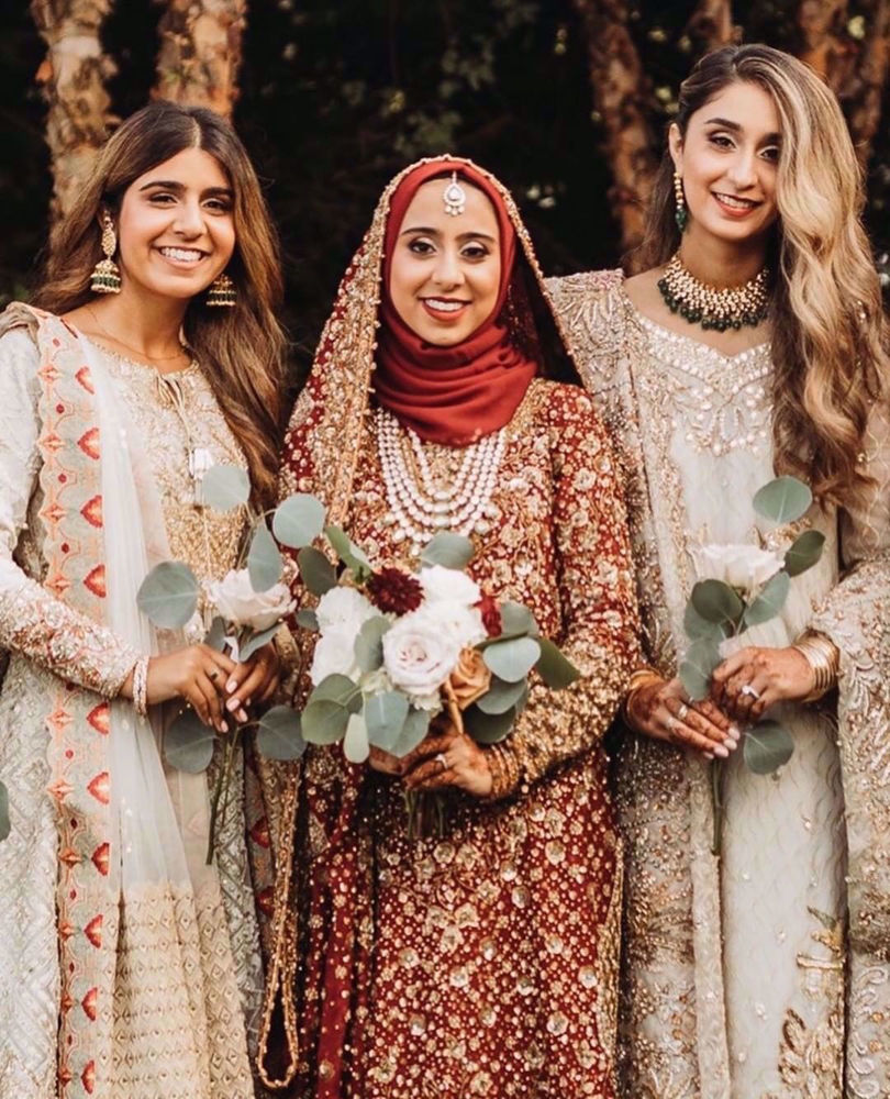 Picture of Marriyah Simjee, resplendent at her wedding in traditional shades of reds featuring intricate embellishments in gorgeous, glistening golds