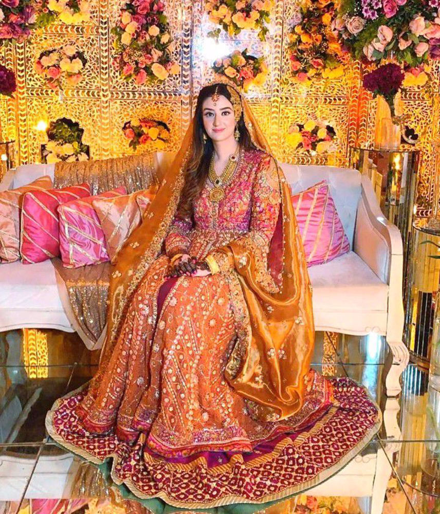 Picture of Minahil Buksh is resplendent in a signature #FarahTalibAziz kalidaar in burnt orange with a vibrant magenta lehnga, accentuated with gold embellishments and a stunning gold dupatta