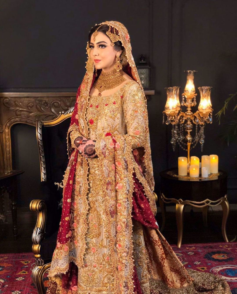 Picture of Maha looks absolutely ravishing at her wedding in a signature #FarahTalibAziz ensemble. A gold kameez offset with a scarlet dupatta, accentuated with gold embellishments and threadwork in shades of peach and scarlet