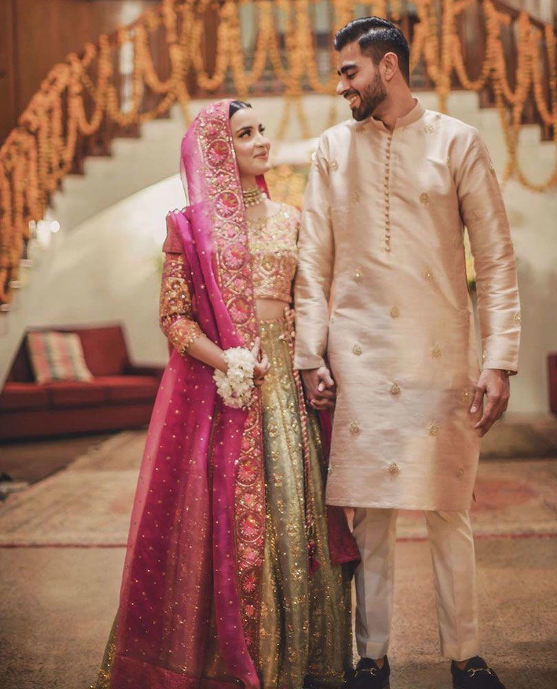 Picture of Aliya Hasnain, is beautiful at her mehndi in a striking #FarahTalibAziz ensemble. A kiwi green lehnga choli offset with a rich magenta dupatta, delicately detailed with gold embellishments and eye-catching work