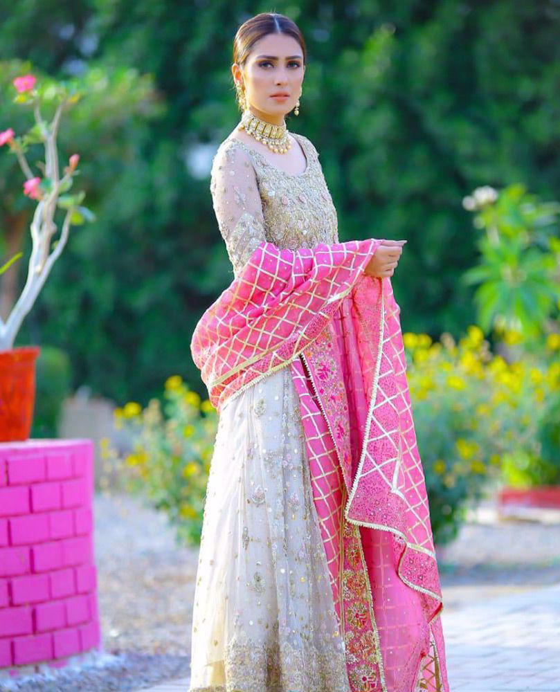 Picture of The spectacular #AyezaKhan is exquisite in a signature ivory #FarahTalibAziz kalidaar. A candy pink organza dupatta, accentuated with gold embroidery and gota provides a striking pop of color